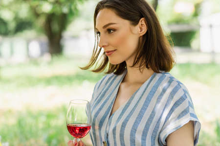 Young woman holding glass of wine in park