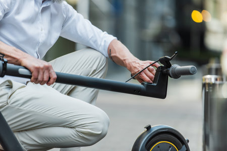 cropped view of mature man adjusting electric scooter on streetの写真素材
