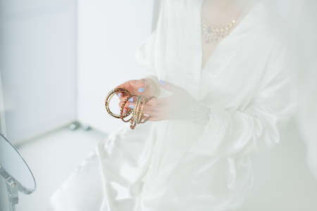 cropped view of young indian bride holding bracelets near mirror