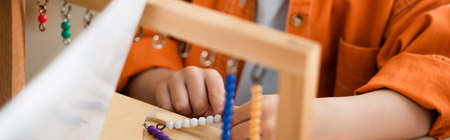 cropped view of boy playing educational game in montessori school, banner