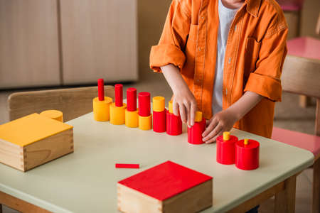 cropped view of boy combining red and yellow blocks in montessori schoolの写真素材