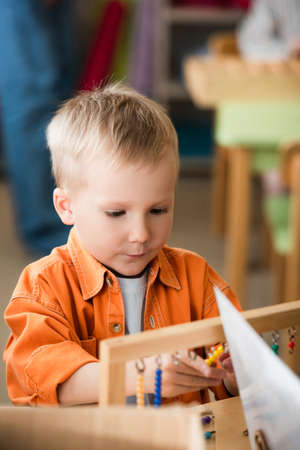 child counting colorful beads while playing educational game in montessori schoolの写真素材