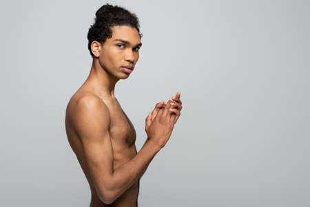 shirtless african american man with perfect skin looking at camera while standing isolated on gray, beauty conceptの写真素材