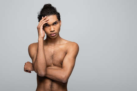 shirtless african american man holding hand near face while looking at camera isolated on gray, beauty conceptの写真素材