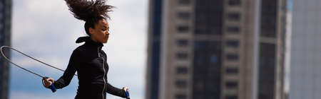 Fit african american sportswoman working out with jump rope outdoors, bannerの写真素材