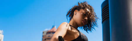 Low angle view of african american sportswoman in earphone looing at camera, bannerの写真素材
