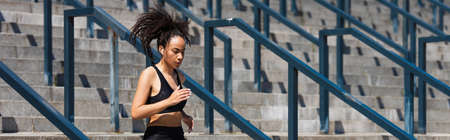 African american sportswoman listening music while running on stairs, banner