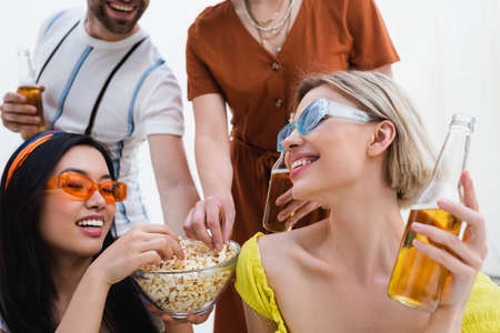 happy multiethnic friends eating popcorn during beer partyの写真素材