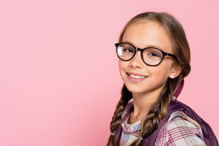 Portrait of smiling schoolkid in eyeglasses isolated on pink