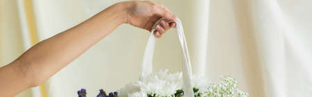 cropped view of woman holding fabric shopper bag with flowers on white, banner