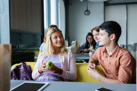 teenage friends talking during lunch break in school canteenの写真素材