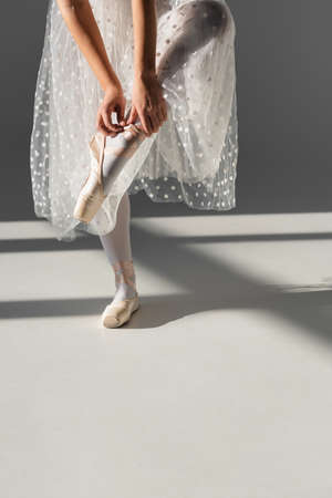 Cropped view of ballerina wearing pointe shoe on gray background with shadowの写真素材