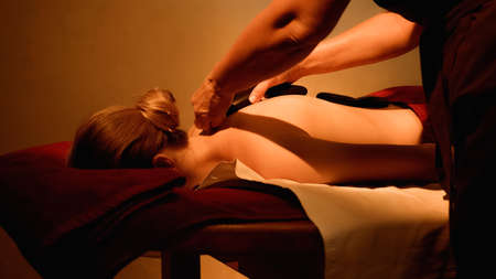 young woman receiving hot stone massage in spa salonの写真素材