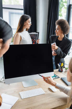 blurred businesswoman pointing with pen at monitor with blank screen mear multiethnic managersの写真素材
