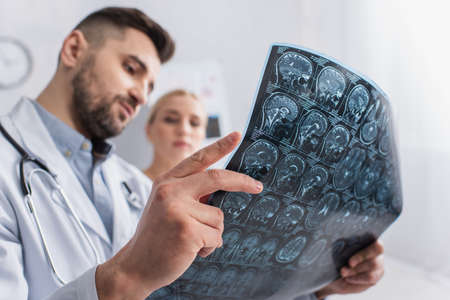 blurred doctor and patient looking at brain mri scan in hospitalの写真素材