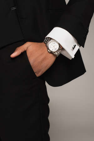 cropped view of african american man in black formal wear and wristwatch holding hand in pocket...