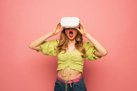 shocked woman in vr headset isolated on pink