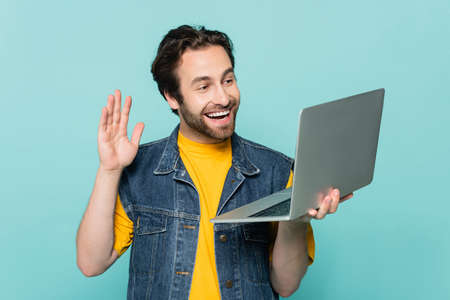 Smiling man having video call on laptop isolated on blueの写真素材