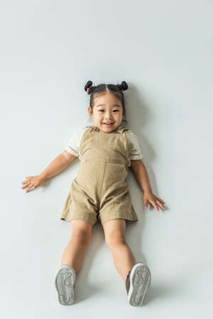 high angle view of happy asian toddler girl lying on gray