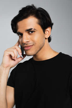 smiling young man talking on cellphone isolated on grayの写真素材