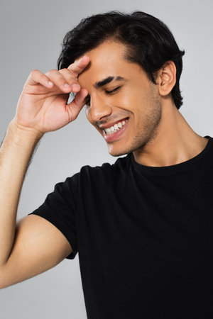young cheerful man in black t-shirt posing isolated on grayの写真素材