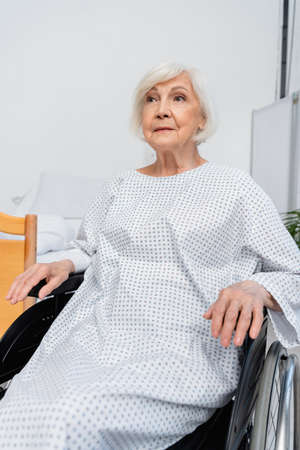 Elderly patient sitting in wheelchair in hospital wardの写真素材