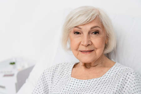Elderly woman smiling at camera in hospital ward