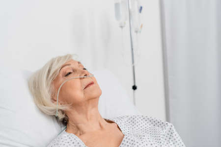 Elderly patient with nasal cannula lying in hospital wardの写真素材