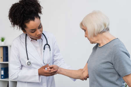 African american doctor with stethoscope touching arm of patientの写真素材