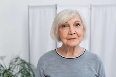 Elderly woman looking at camera in hospitalの写真素材