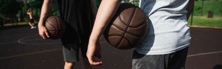 Cropped view of men holding basketball balls outdoors, bannerの写真素材