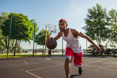 African american sportsman playing basketball on outdoor playground