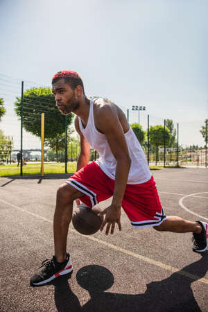 African american sportsman playing basketball on playground at daytimeの写真素材