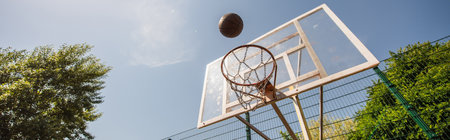 Low angle view of basketball ball near hoop outdoors, bannerの写真素材