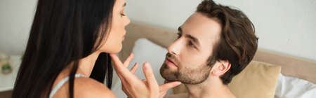 bearded man touching chin of brunette woman, banner