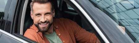 Bearded driver looking at camera from car, banner