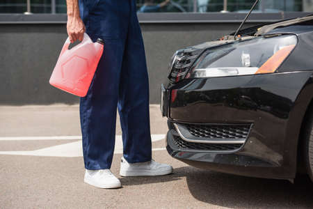 Cropped view of mechanic holding canister with windshield washer fluid near carの写真素材