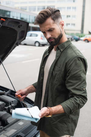 Confused driver checking oil of motor near car outdoorsの写真素材