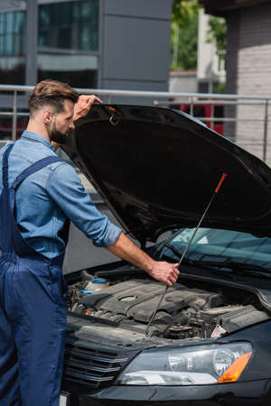 Side view of mechanic opening hood of car outdoorsの写真素材