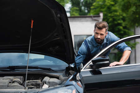 Mechanic standing near door of car outdoors
