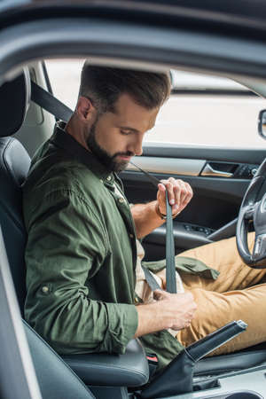 Side view of driver holding safety belt in car