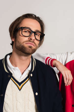 stylish man in eyeglasses looking at camera near woman leaning on his shoulder isolated on gray