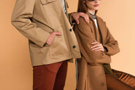 cropped view of man touching shoulder of stylish woman while standing with hand in pocket isolated...