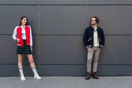 happy couple in fashionable clothes posing near gray wall outdoorsの写真素材