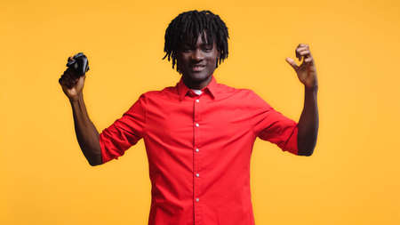 excited african american man holding joystick isolated on yellowの写真素材