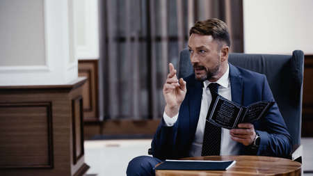Businessman holding menu and gesturing in lobby of restaurant