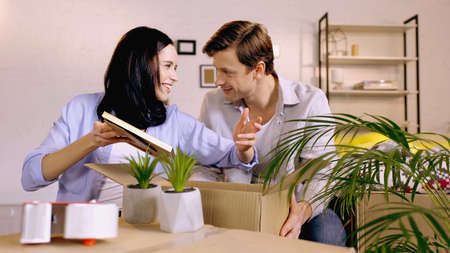 Couple talking and packing photo frame in box at homeの写真素材