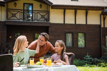 Smiling woman touching husband near daughter during picnic outdoorsの写真素材