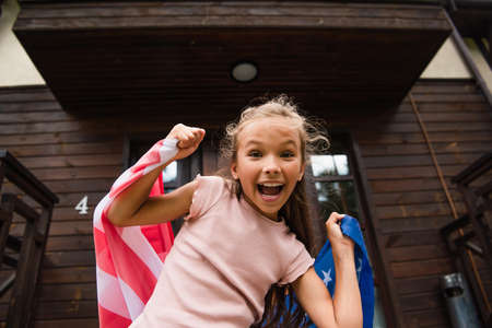 Excited girl holding american flag outdoorsの写真素材