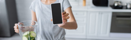 cropped view of blurred woman showing smartphone with blank screen near shaker with zucchini, banner